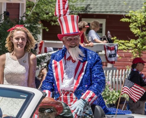 Uncle Sam wearing patriotic outfit riding in a car