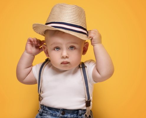 Child wearing striped suspenders and striped hat