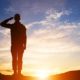Rear view of soldier saluting at sunset